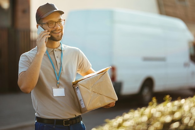 happy courier communicating cell phone while making delivery city 637285 2308